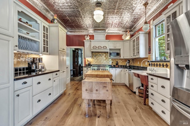 kitchen featuring light hardwood / wood-style floors, hanging light fixtures, appliances with stainless steel finishes, decorative backsplash, and butcher block countertops