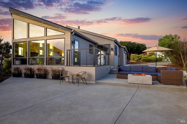 back house at dusk featuring a patio area and an outdoor living space with a fire pit