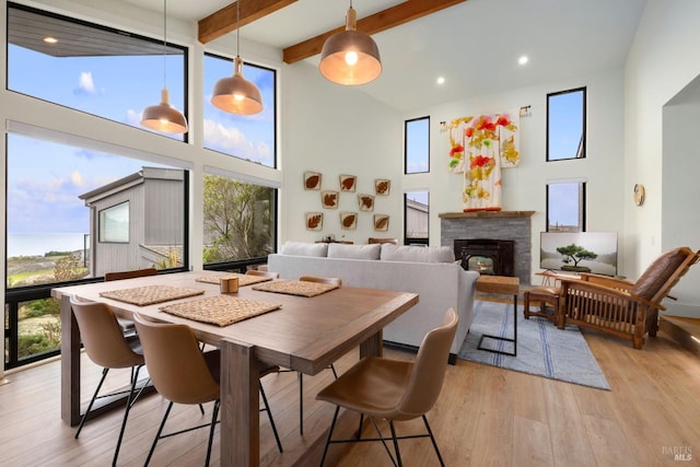 dining room with a towering ceiling, beam ceiling, and light hardwood / wood-style floors