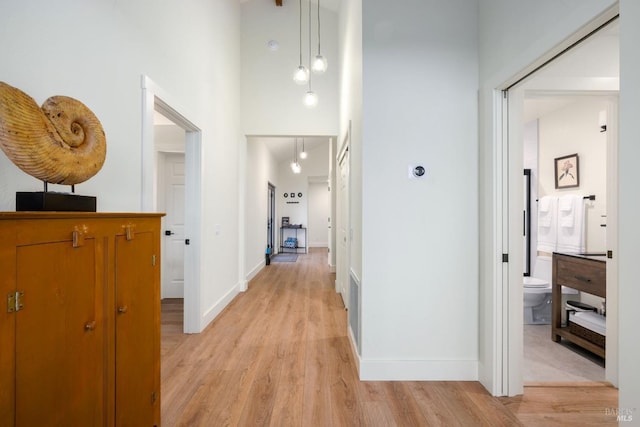 corridor featuring a high ceiling and light wood-type flooring