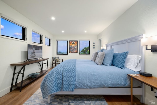 bedroom with multiple windows and hardwood / wood-style flooring