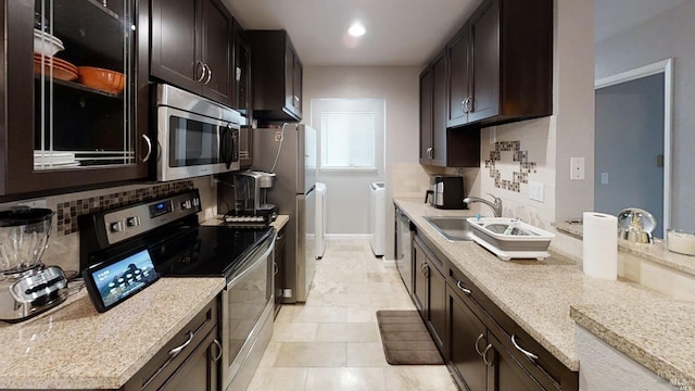 kitchen featuring decorative backsplash, appliances with stainless steel finishes, sink, and separate washer and dryer