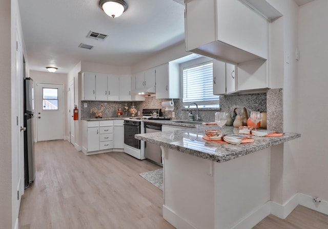 14090 Pine St, Walnut Grove, CA 95690 - kitchen featuring appliances with stainless steel finishes, a peninsula, light wood-style flooring, decorative backsplash, and under cabinet range hood