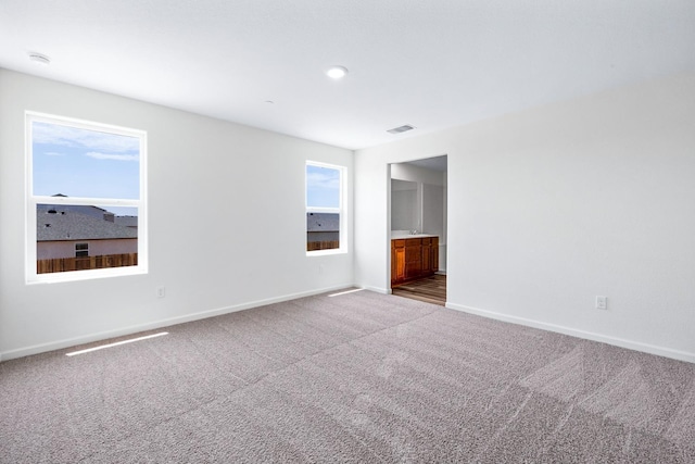 spare room with carpet, visible vents, and baseboards