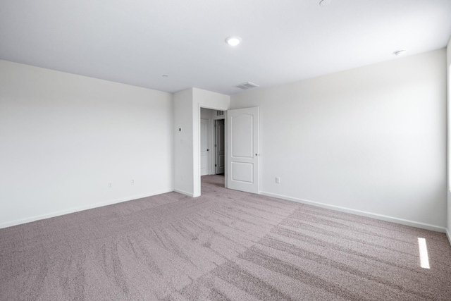 empty room with light colored carpet, visible vents, and baseboards