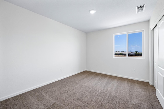 empty room with carpet, visible vents, and baseboards