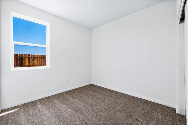 empty room with dark colored carpet and baseboards