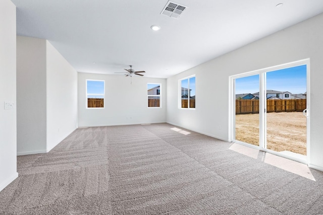 spare room with light carpet, ceiling fan, visible vents, and baseboards