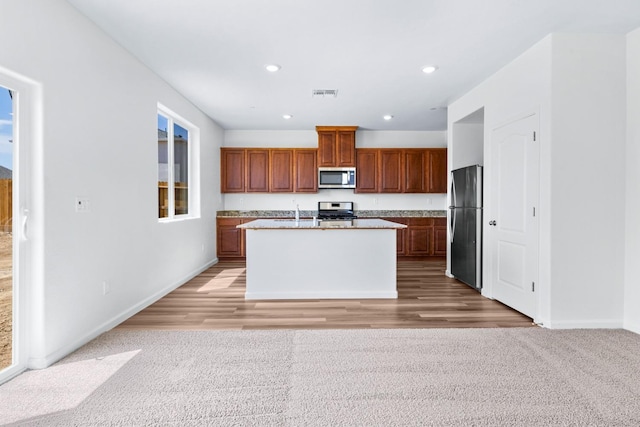 kitchen featuring brown cabinets, a center island with sink, recessed lighting, visible vents, and appliances with stainless steel finishes