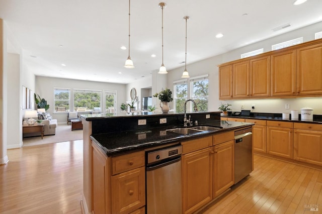 kitchen with pendant lighting, a healthy amount of sunlight, sink, stainless steel dishwasher, and a center island with sink