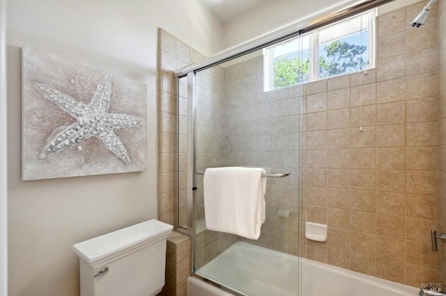 bathroom featuring combined bath / shower with glass door and toilet