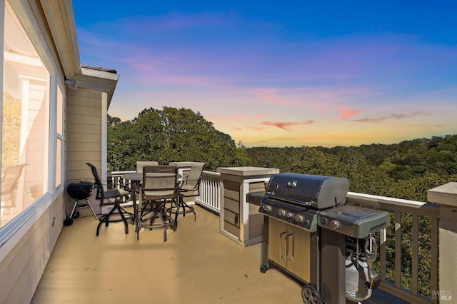 patio terrace at dusk featuring a balcony and a grill