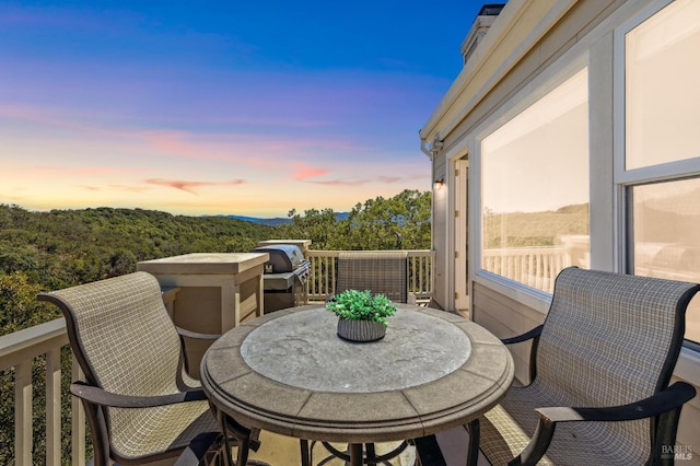 balcony at dusk featuring area for grilling