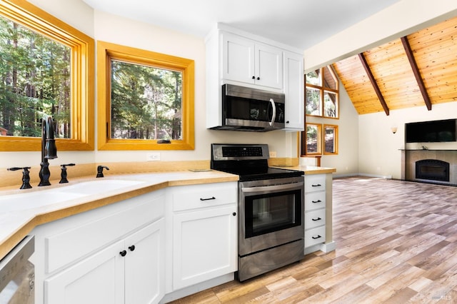 kitchen featuring sink, lofted ceiling with beams, appliances with stainless steel finishes, light hardwood / wood-style flooring, and wood ceiling