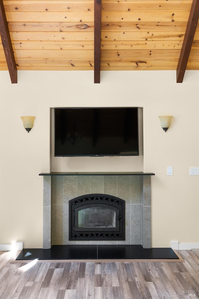 details with beamed ceiling, wooden ceiling, wood-type flooring, and a tile fireplace