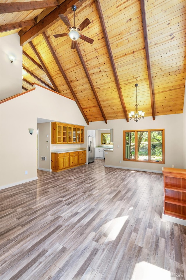 unfurnished living room with ceiling fan with notable chandelier, wood ceiling, beamed ceiling, hardwood / wood-style floors, and high vaulted ceiling