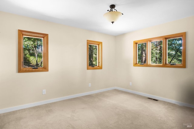 unfurnished room with light carpet, plenty of natural light, visible vents, and baseboards