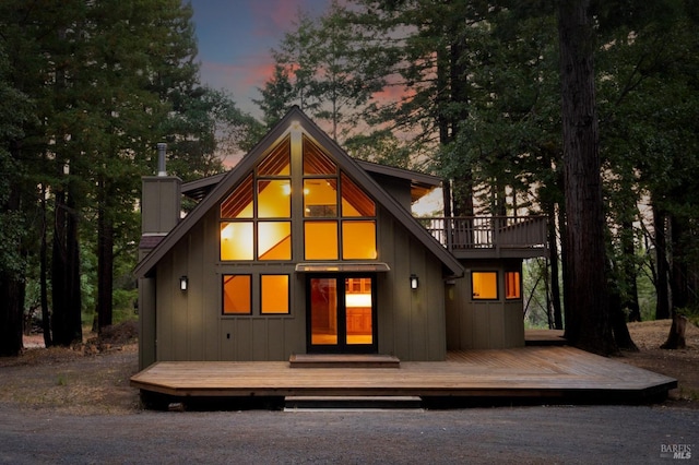 view of front of house featuring a chimney, a deck, and board and batten siding