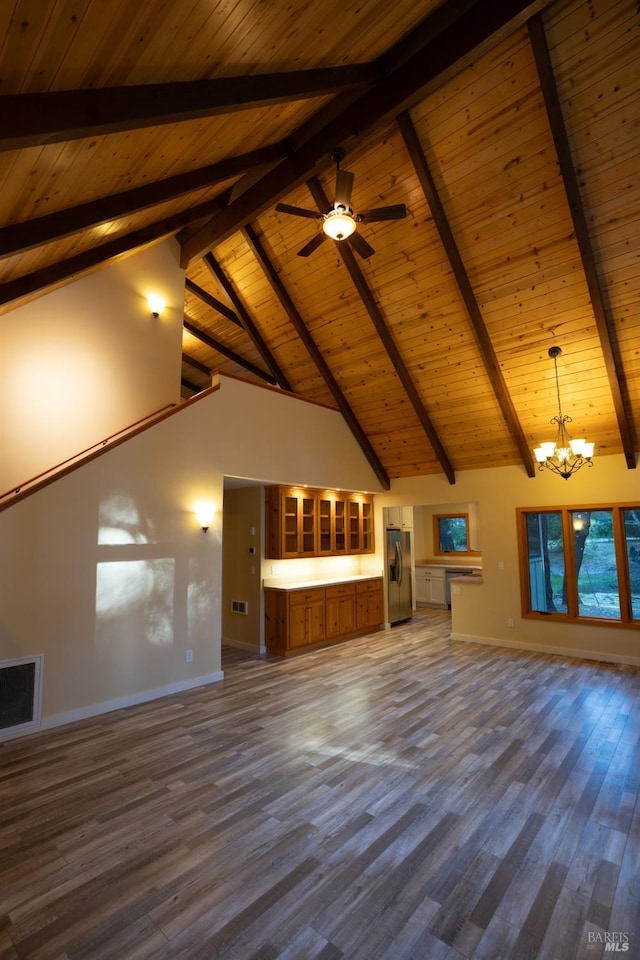 unfurnished living room with high vaulted ceiling, ceiling fan with notable chandelier, dark wood-style flooring, visible vents, and baseboards