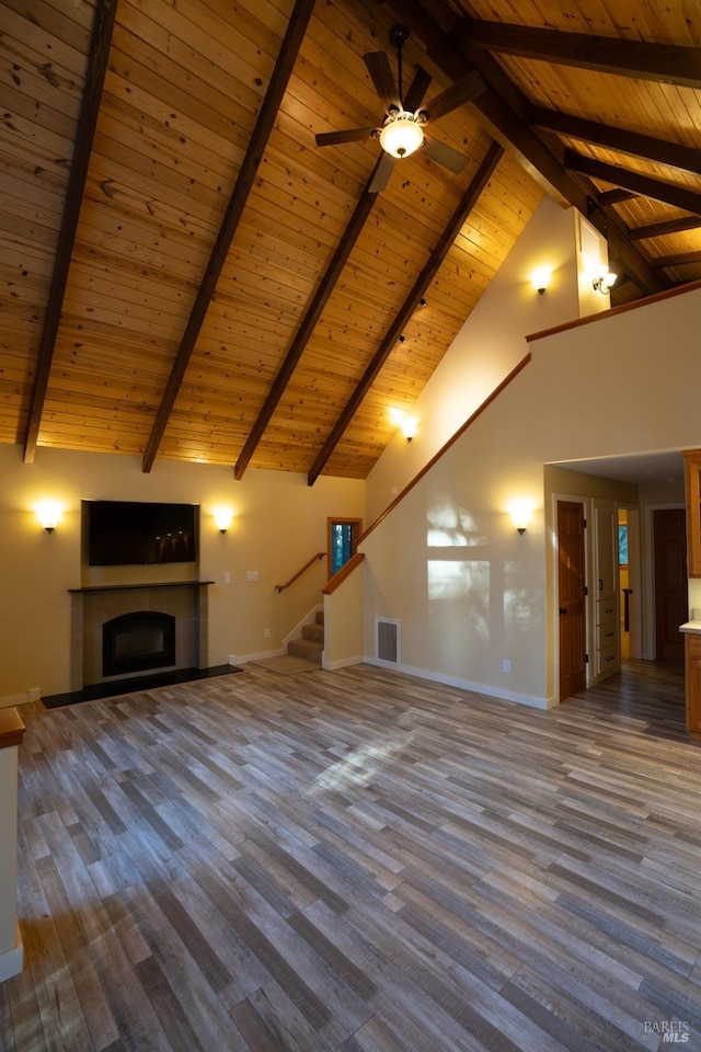 unfurnished living room featuring high vaulted ceiling, a tiled fireplace, wood finished floors, and baseboards