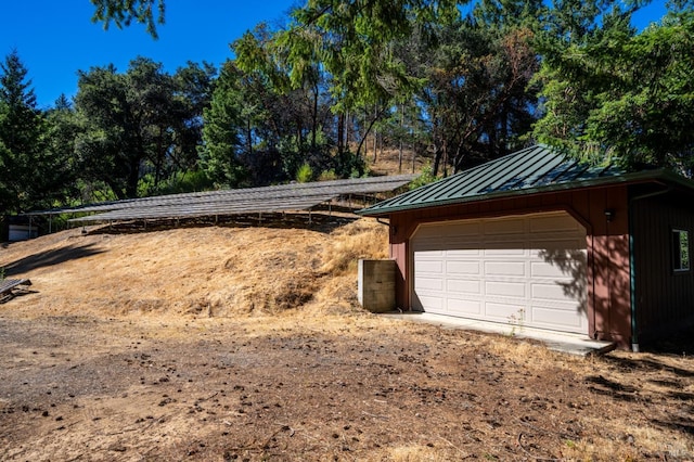 view of home's exterior with a garage, an outbuilding, a standing seam roof, and metal roof