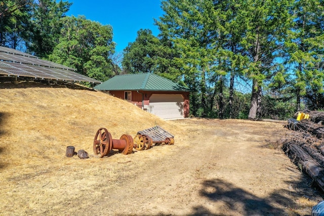 view of yard featuring a garage, an outdoor structure, and dirt driveway