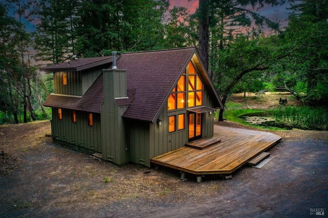 rear view of house featuring board and batten siding and roof with shingles