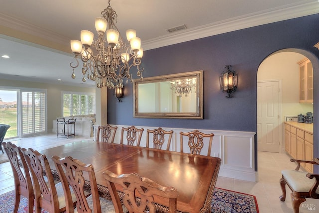 tiled dining space featuring crown molding and a chandelier