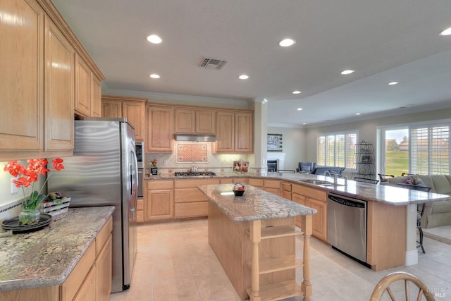 kitchen featuring sink, a center island, kitchen peninsula, stainless steel appliances, and light brown cabinets