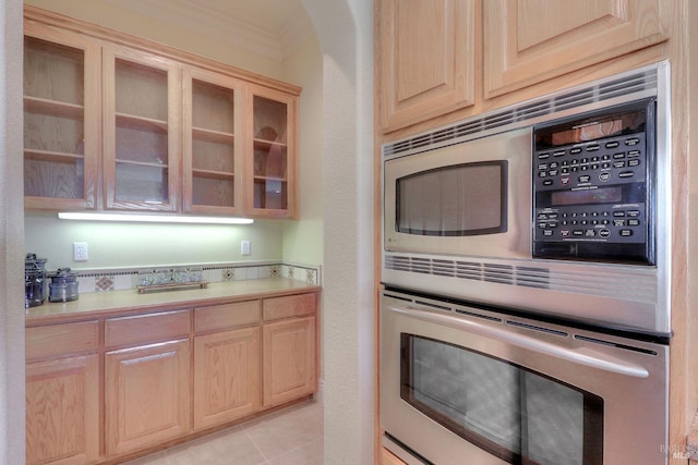 kitchen with light tile patterned flooring, stainless steel microwave, and light brown cabinetry