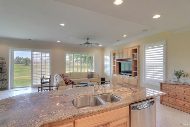 kitchen featuring a wealth of natural light, light brown cabinetry, dishwasher, sink, and light stone counters