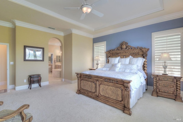 carpeted bedroom featuring crown molding, ensuite bathroom, and ceiling fan