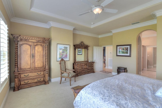 carpeted bedroom featuring crown molding, ensuite bathroom, and a raised ceiling