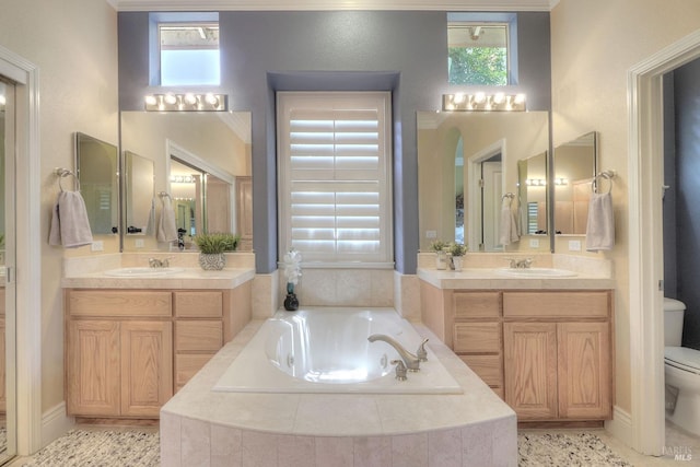 bathroom featuring vanity, tiled bath, and toilet