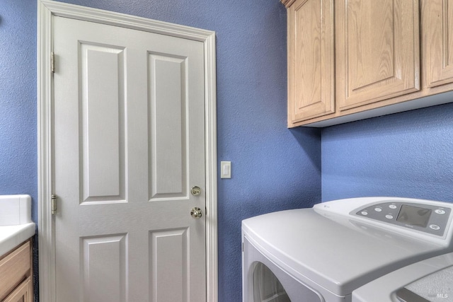 clothes washing area featuring cabinets and washing machine and clothes dryer