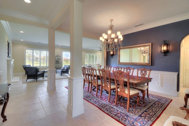 tiled dining space featuring crown molding, a chandelier, and ornate columns