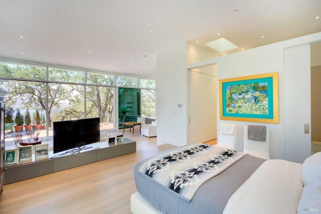 bedroom featuring recessed lighting, a skylight, a wall of windows, and wood finished floors