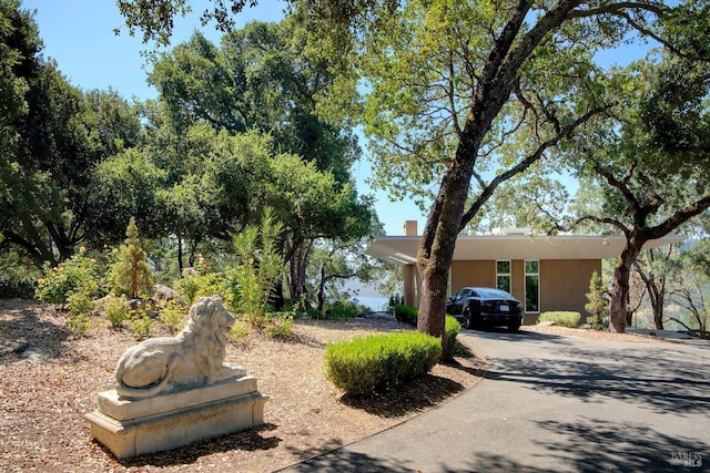view of front facade with stucco siding, driveway, and a chimney