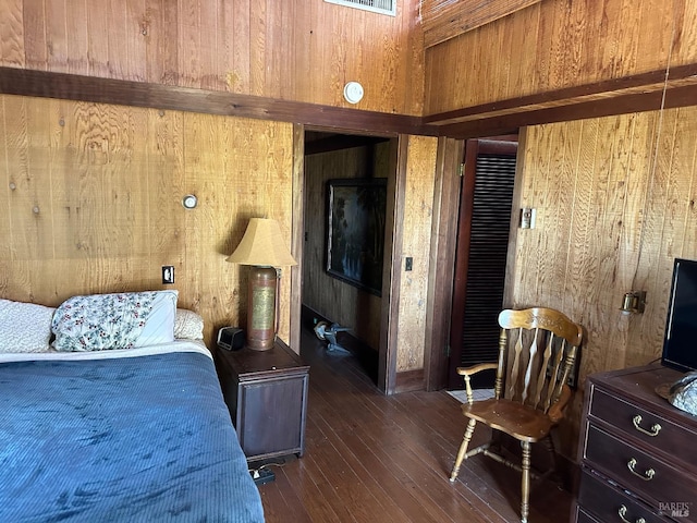 bedroom with dark hardwood / wood-style floors and wooden walls