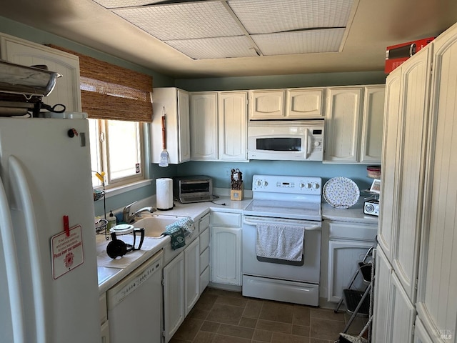 kitchen featuring sink, dark tile patterned floors, white cabinets, and white appliances