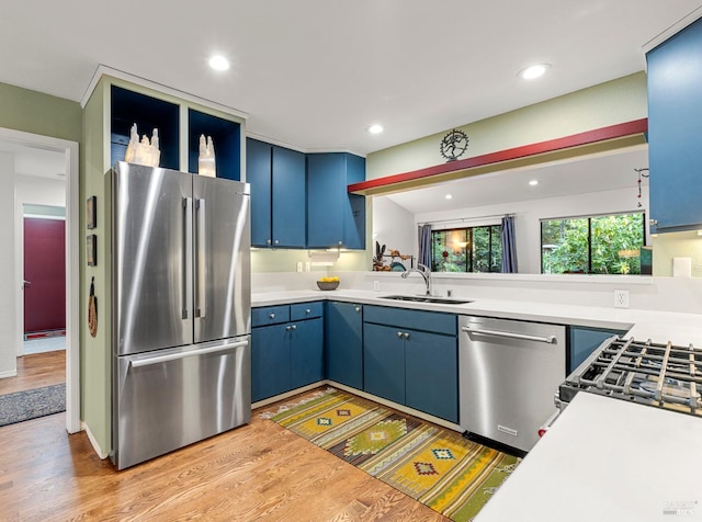 kitchen with blue cabinetry, appliances with stainless steel finishes, light countertops, and a sink