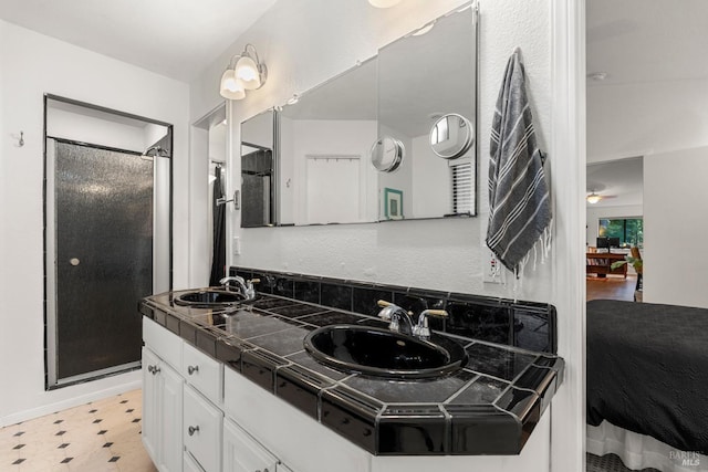 full bath with double vanity, a shower stall, a sink, and tile patterned floors