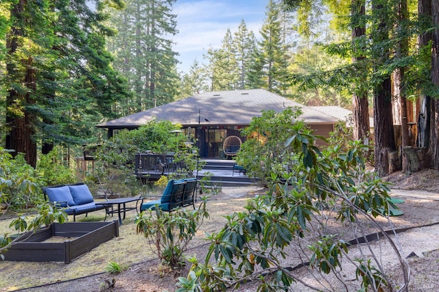 exterior space featuring a shingled roof, a garden, and a deck