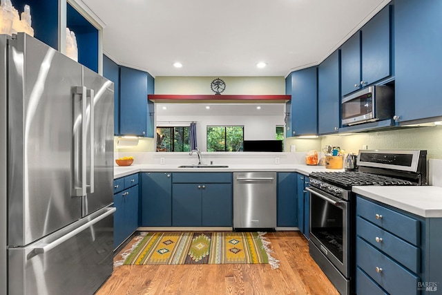 kitchen featuring stainless steel appliances, light countertops, a sink, and blue cabinetry