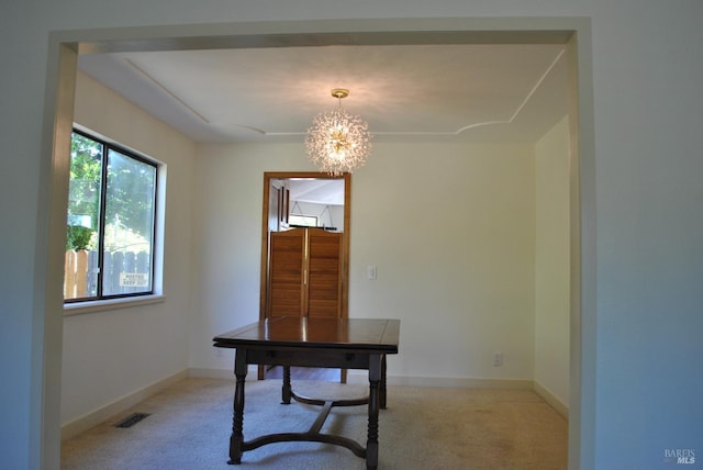 carpeted office with an inviting chandelier