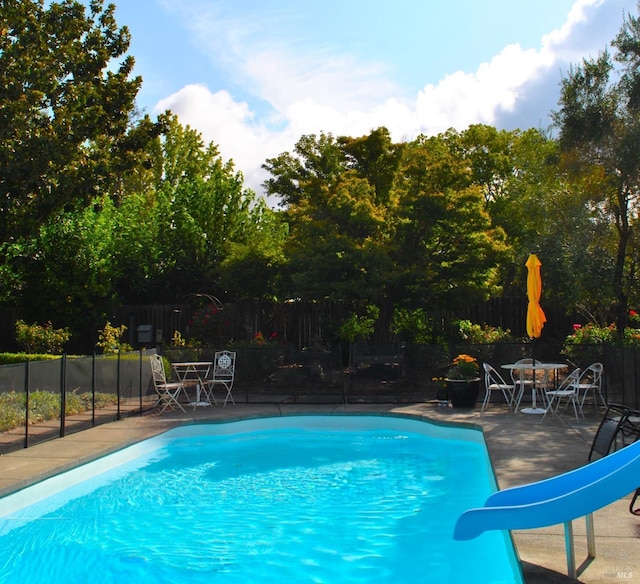 view of pool with a water slide and a patio