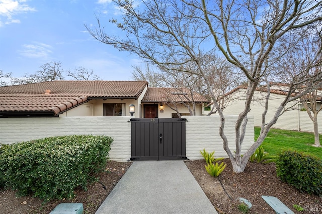 view of front facade featuring a fenced front yard, a gate, a tiled roof, and stucco siding