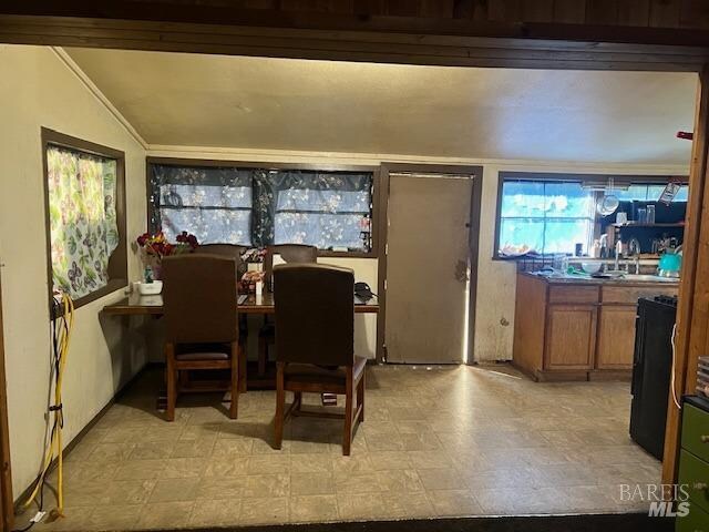 tiled dining room featuring sink and vaulted ceiling