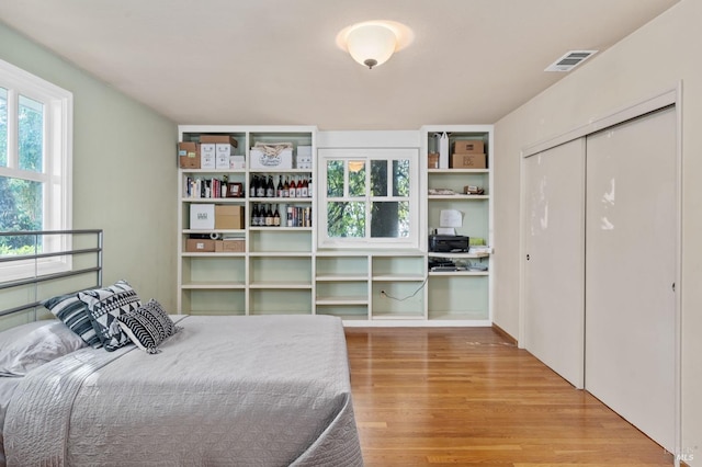 bedroom with wood-type flooring, built in desk, and a closet