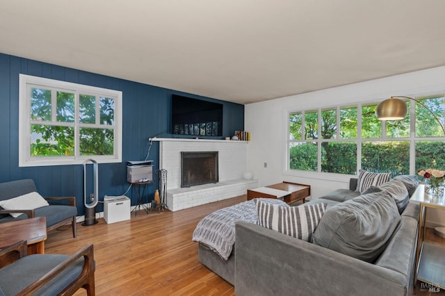 living room with a brick fireplace and wood-type flooring